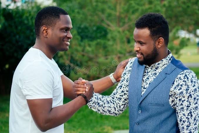 Friends shaking hands in a firm, smiling grip outdoors